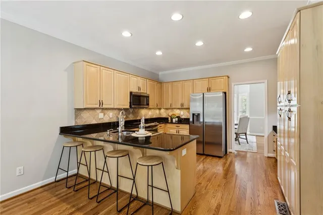 a kitchen with stainless steel appliances granite countertop a refrigerator a stove top oven a sink and cabinets