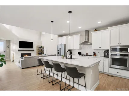 a kitchen with stainless steel appliances kitchen island granite countertop a sink a stove a dining table and chairs