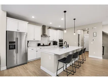 a kitchen with stainless steel appliances a refrigerator a stove a sink a dining table and chairs