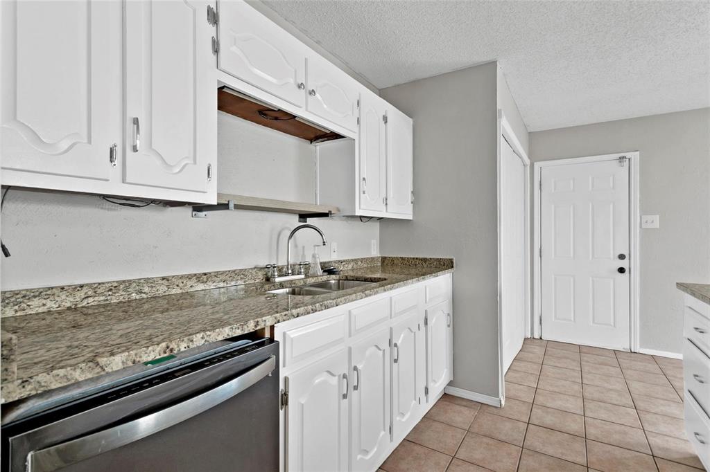 6104 Kelly Elliott Road Arlington, TX 76001 - Photo 14 of 25 a kitchen with granite countertop a sink stove and cabinets