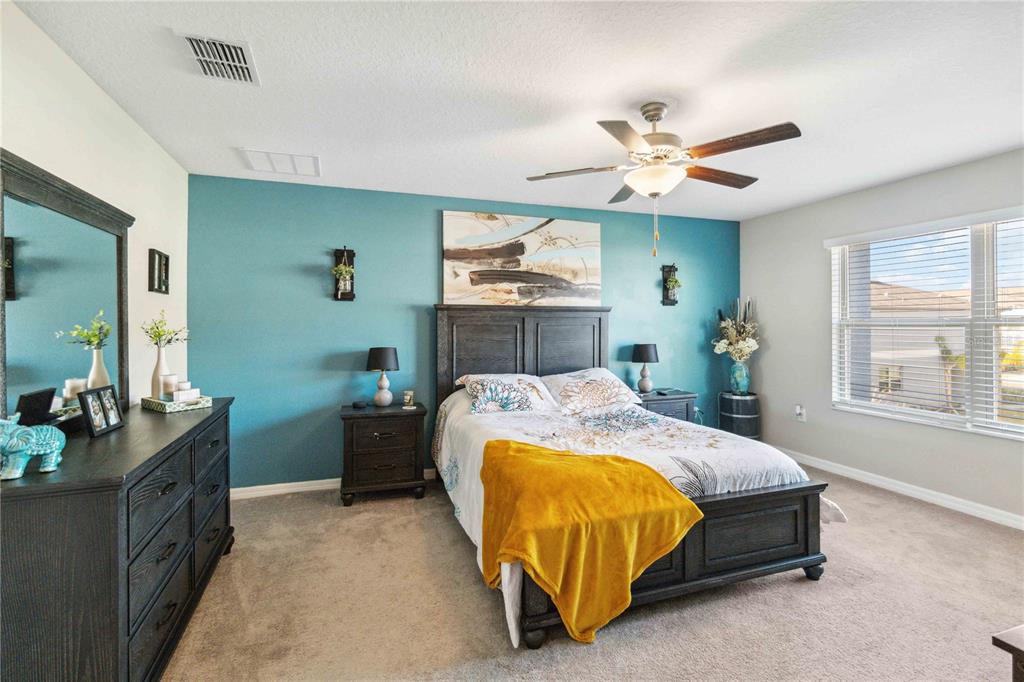 14339 Easy Goer Street Ruskin, FL 33573 - Photo 36 of 49 a spacious bedroom with a bed and a chandelier