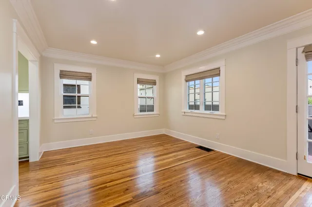 a view of an empty room with window and wooden floor