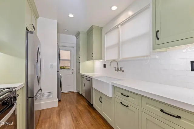 a kitchen with stainless steel appliances a sink dishwasher stove and cabinets with wooden floor