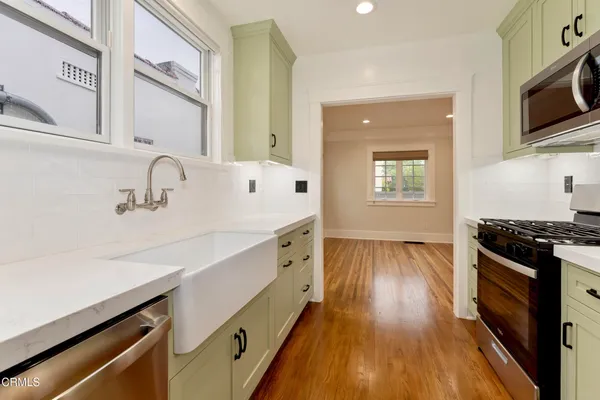 a kitchen with stainless steel appliances a sink cabinets and wooden floor