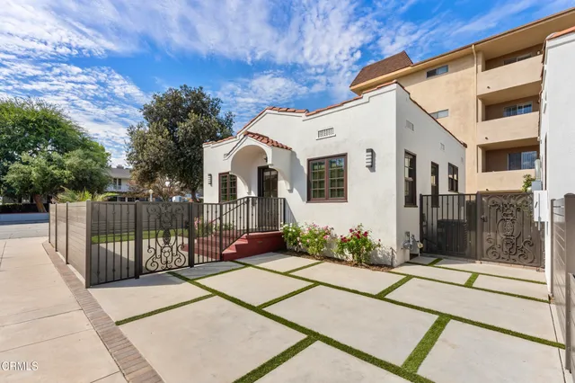 a view of a white house with many windows next to a yard