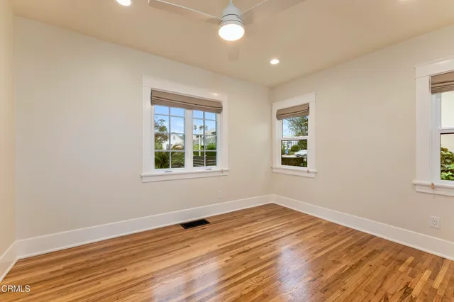 an empty room with wooden floor and windows