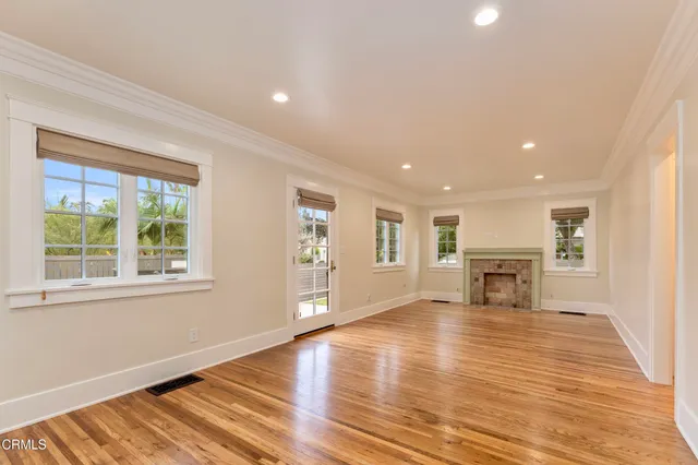 an empty room with wooden floor a fireplace and windows
