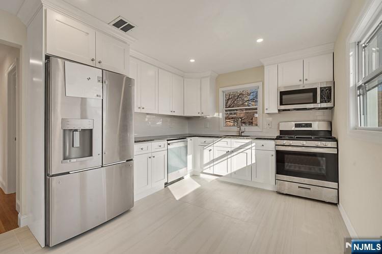a kitchen with granite countertop white cabinets and stainless steel appliances