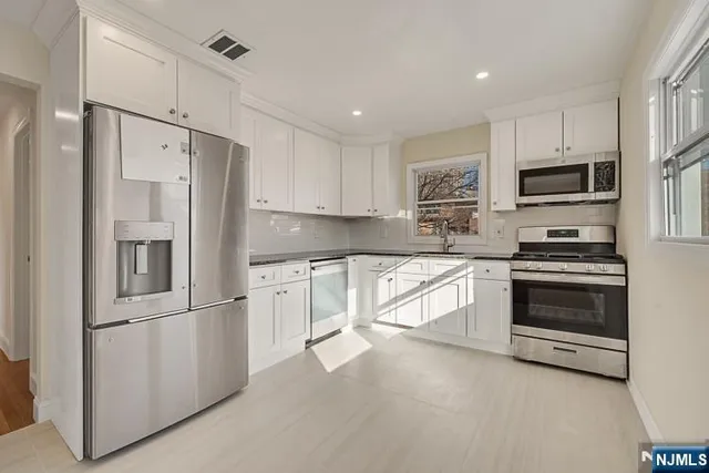a kitchen with granite countertop white cabinets and stainless steel appliances