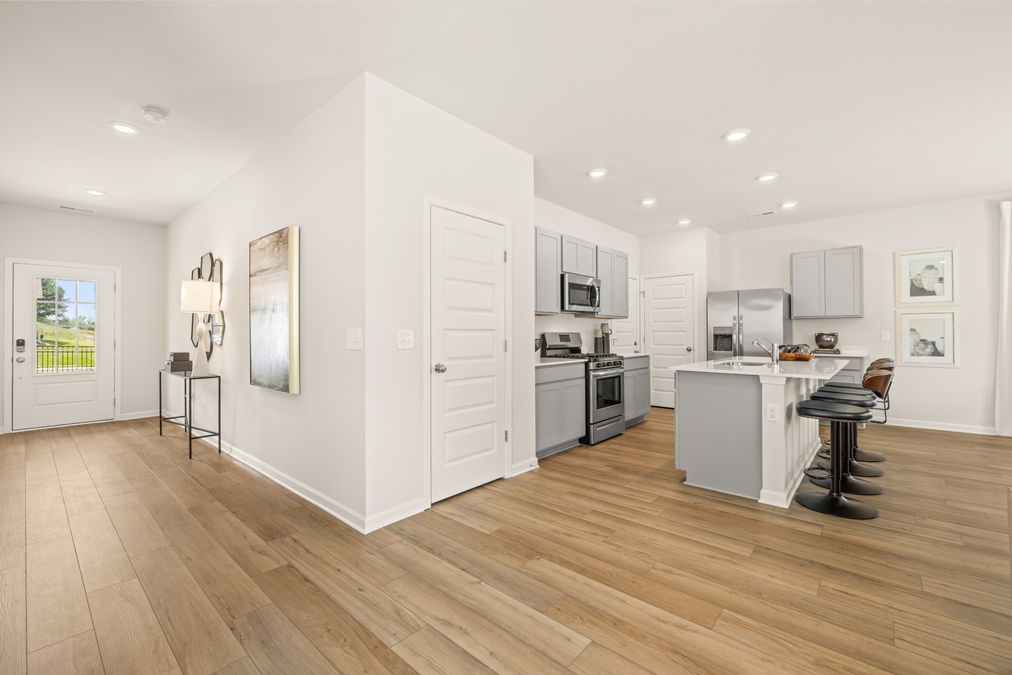 Entry leads to spacious, open concept main level with beautiful and durable LVP flooring throughout. Photo of decorated model home of this floorplan, not actual home listed.