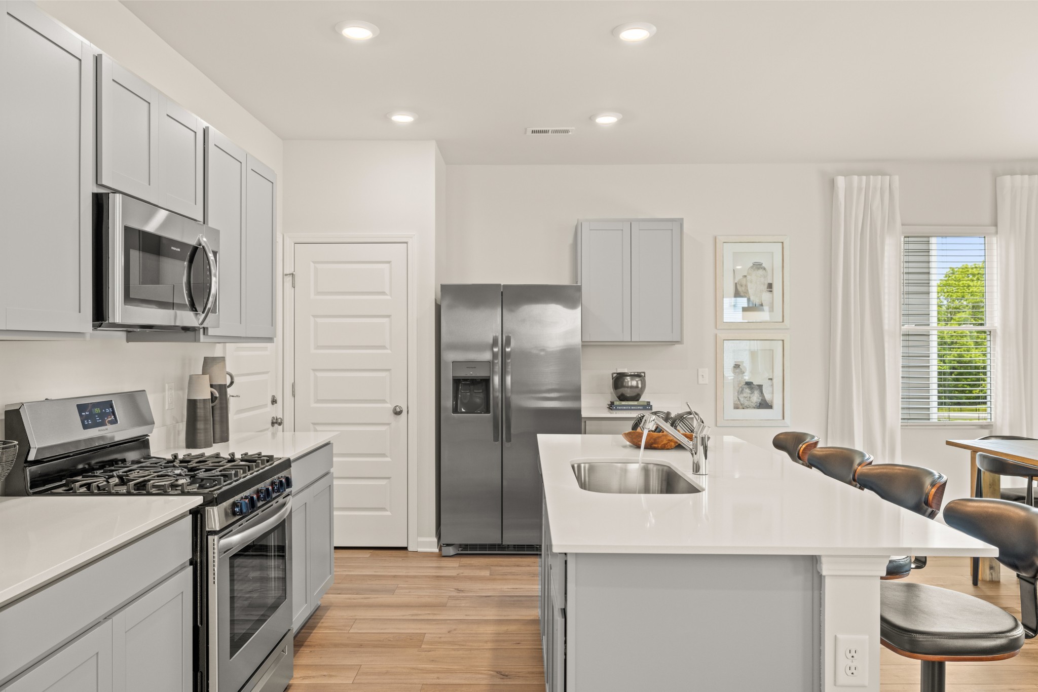 Fabulous kitchen with shaker style cabinetry, quartz countertops, gas cooking, large single bowl sink, pantry, and all appliances included. Photo of decorated model home of this floorplan, not actual home listed.