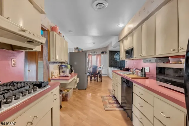 a kitchen with stainless steel appliances granite countertop a stove top oven a sink dishwasher and cabinets with wooden floor