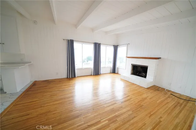 a view of empty room with wooden floor and fireplace