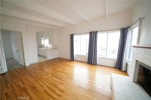 a view of empty room with wooden floor and fireplace