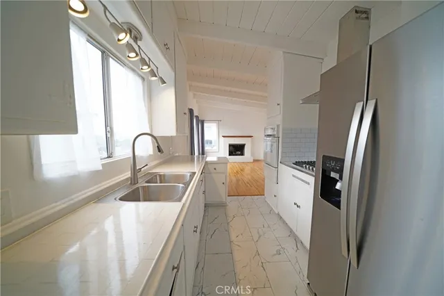 a large white kitchen with a sink a refrigerator and a window