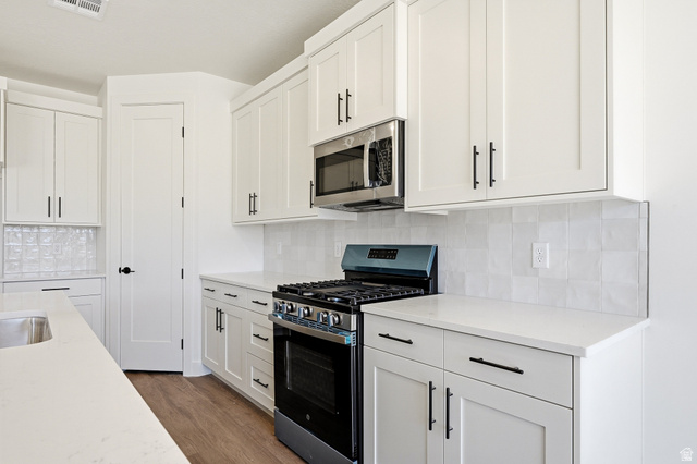 4978 North 75 East Enoch, UT 84721 - Photo 11 of 60 Kitchen featuring stainless steel appliances, white cabinets, tasteful backsplash, and light wood-type flooring