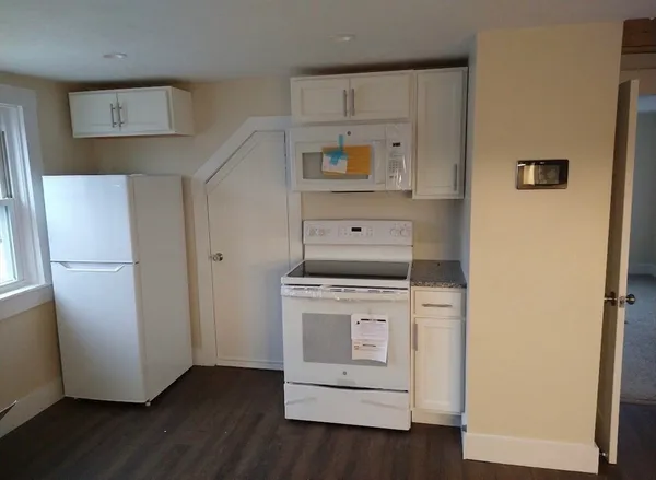 a view of a kitchen with refrigerator and wooden floor