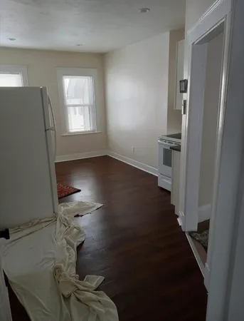 a view of a livingroom with wooden floor and a kitchen