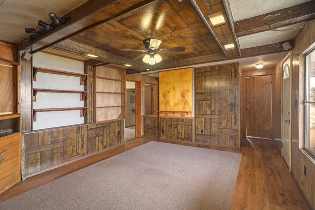 an empty room with wooden floor fan and windows