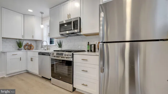 a kitchen with stainless steel appliances white cabinets and a refrigerator