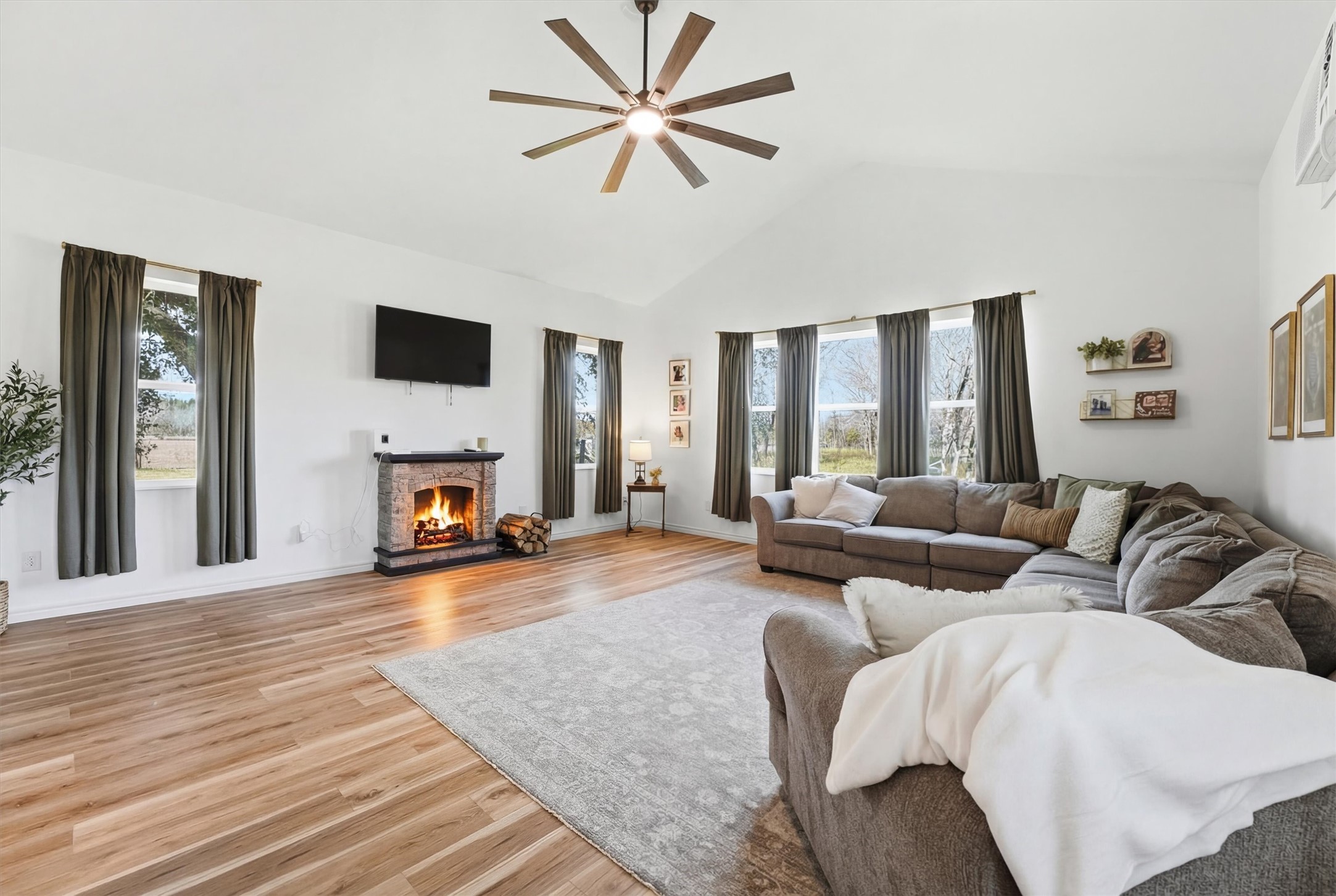 611 Reidland Road Crosby, TX 77532 - Photo 5 of 35 This spacious living room features a high vaulted ceiling with a modern fan, a cozy fireplace, and abundant natural light from large windows.