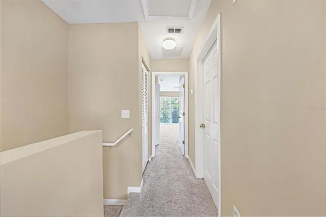 a view of a hallway with wooden floor and a bathroom