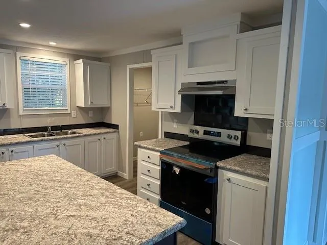 an empty room with wooden floor cabinet and windows