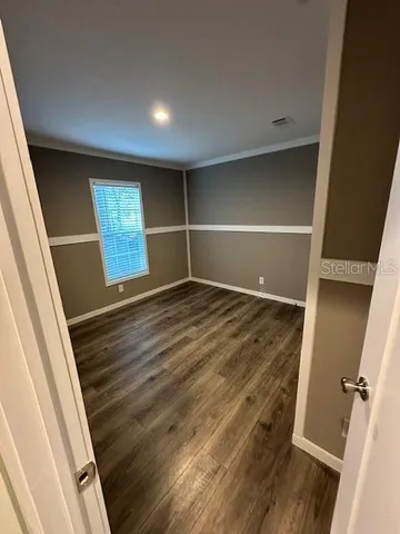 a view of an empty room with wooden floor and closet