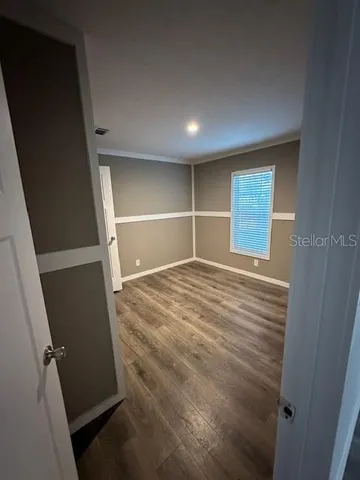 an empty room with wooden floor and entrance