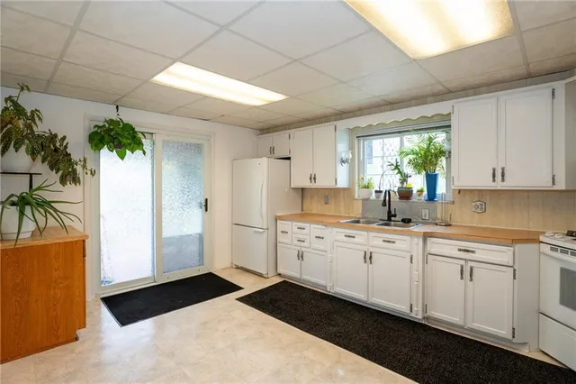 a kitchen with white cabinets a sink a window and stainless steel appliances
