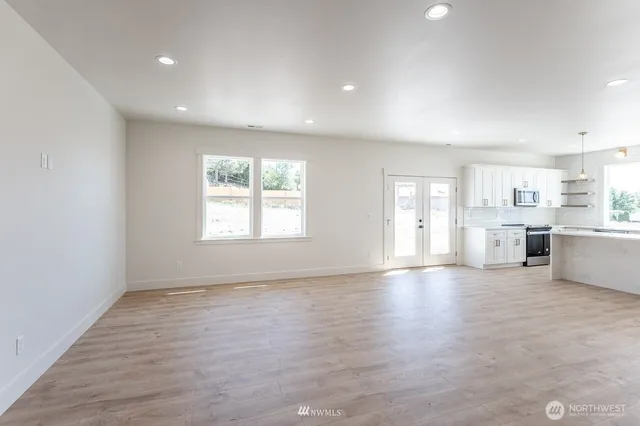 a kitchen with kitchen island a sink dishwasher a stove and white cabinets with wooden floor