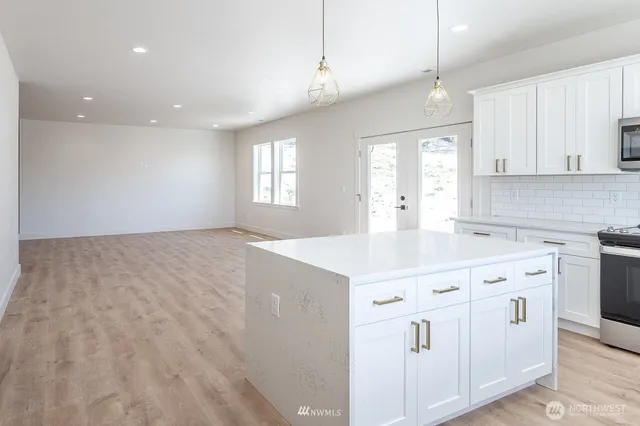 a large white kitchen with a refrigerator a sink dishwasher and a stove top oven with wooden floor