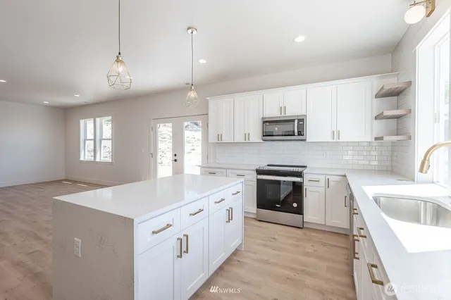 a kitchen with a sink a stove a refrigerator and white cabinets