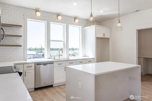 a large kitchen with stainless steel appliances granite countertop a stove a sink a refrigerator a center island and wooden floor