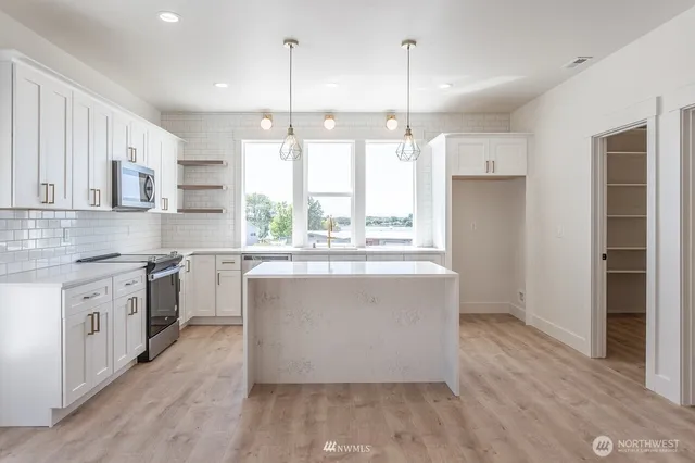 a open kitchen with kitchen island a stove a sink a center island and cabinets