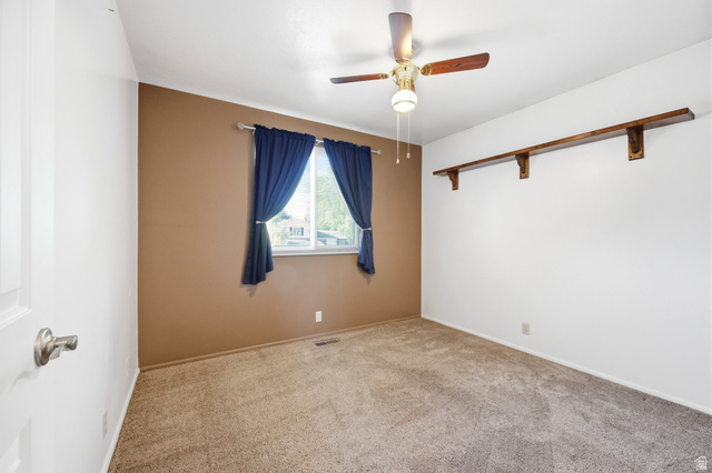 734 Sandy Dunes Drive Sandy, UT 84094 - Photo 21 of 36 Upstairs 3rd bedroom featuring a ceiling fan with light fixture, a window with curtains, and a long wall-mounted shelf