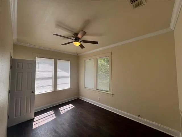 an empty room with wooden floor fan and windows