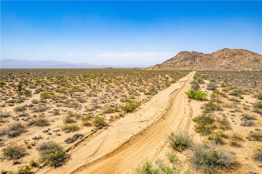 0 East Arroyo Road Yucca, AZ 86438 - Photo 21 of 25 Expansive desert landscape with a clear blue sky, featuring a dirt road and distant rock formations