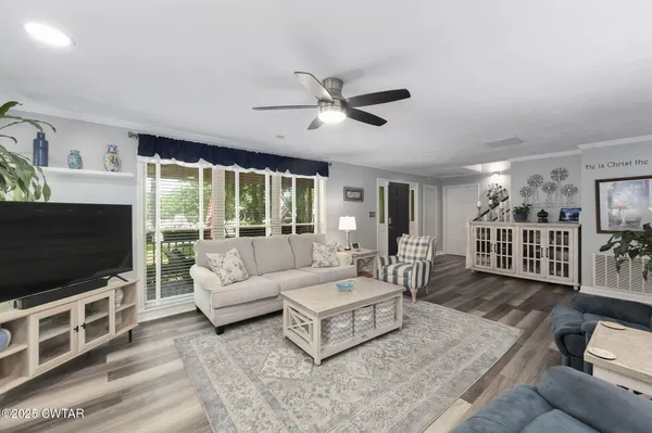a living room with furniture a chandelier fan and a rug