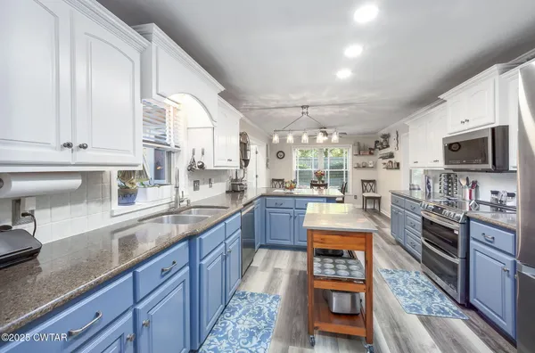 a kitchen with stainless steel appliances granite countertop a sink a stove and a wooden cabinets