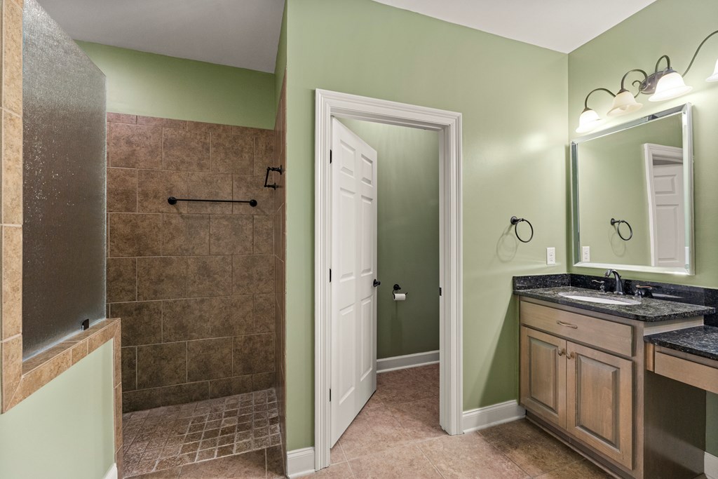 8848 Promenade Place Columbus, GA 31820 - Photo 10 of 21 a bathroom with a granite countertop sink a mirror and a shower