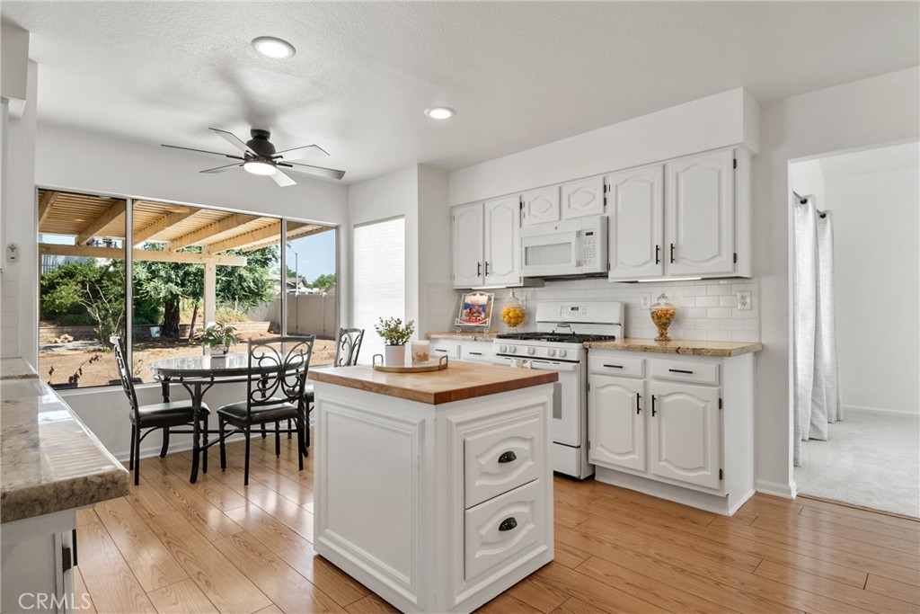 9376 Ruby Red Court Riverside, CA 92508 - Photo 6 of 54 a kitchen with stainless steel appliances granite countertop a stove top oven a sink a dining table and chairs with wooden floor