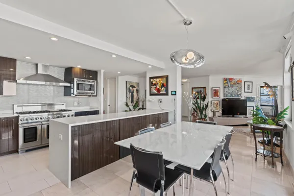 a kitchen with stainless steel appliances a table chairs and a refrigerator