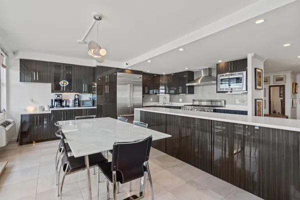 a kitchen with stainless steel appliances a dining table chairs and refrigerator