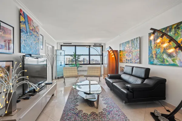 a living room with furniture a flat screen tv and a floor to ceiling window