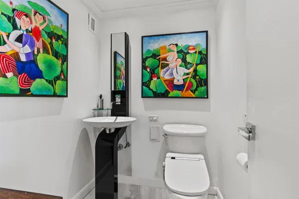 a bathroom with a toilet a sink and painting on the wall
