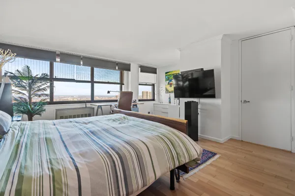 a bedroom with a bed and a flat tv screen on the dresser