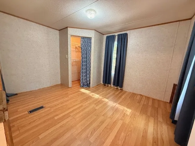 a view of empty room with wooden floor and fan