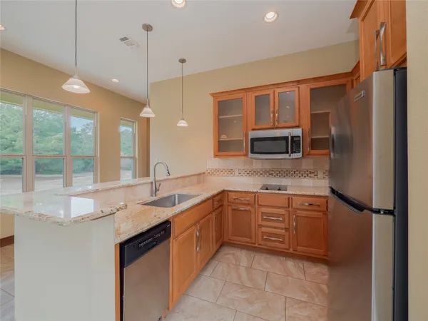 a kitchen with stainless steel appliances granite countertop a sink and a refrigerator