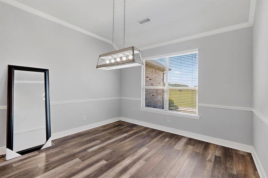 634 Gant Road Sherman, TX 75090 - Photo 19 of 40 Open room with wood-finish flooring, featuring a large window with blinds, crown molding, and wainscoting